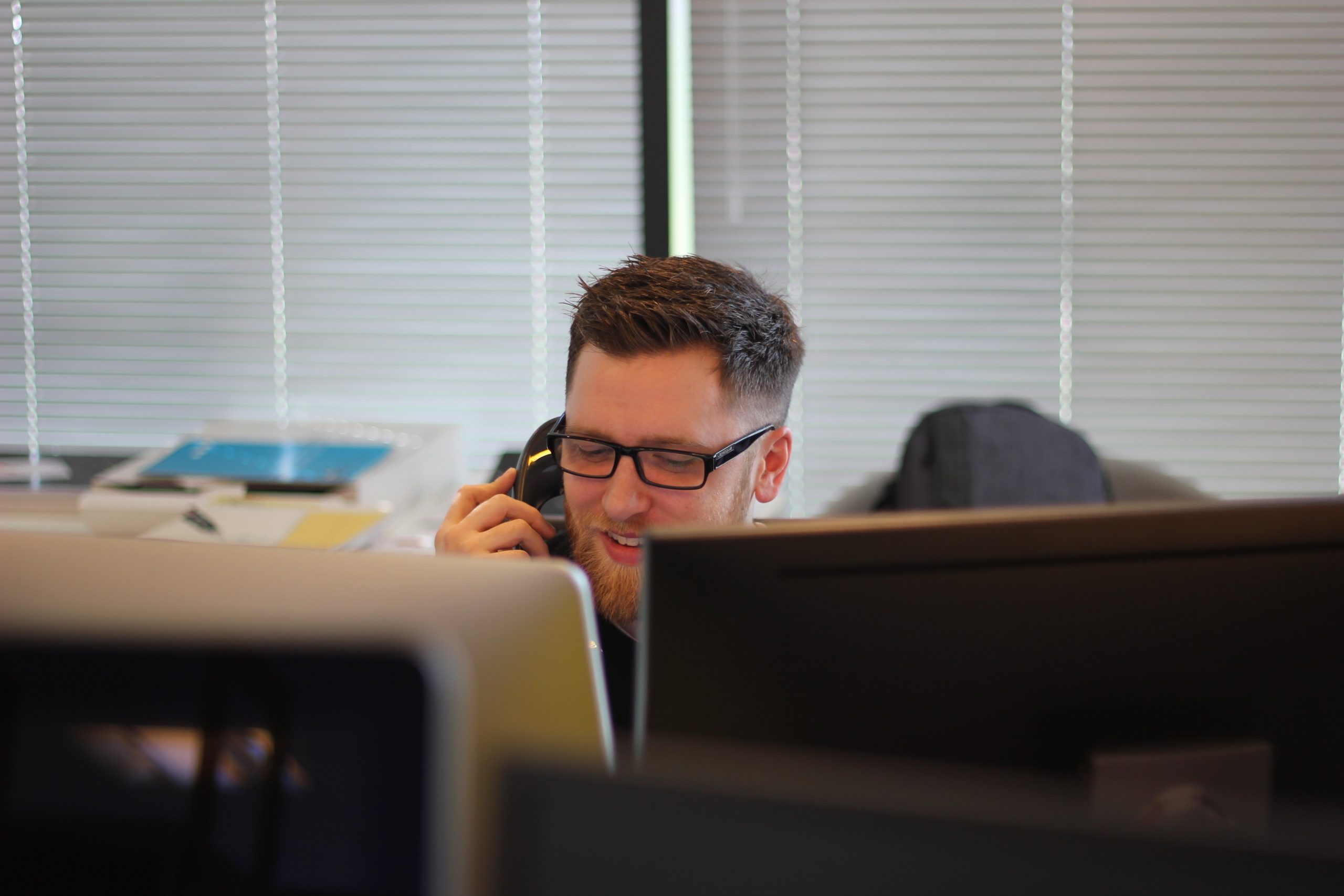 Male DfT Policy Professional sitting at his desk and answering an external phonecall about effective policy-making.