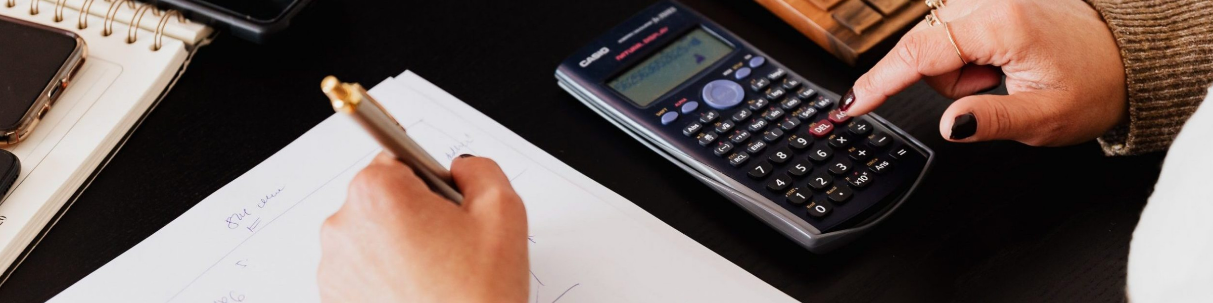 DfT Finance professional sitting at computer desk with calculator and paper.