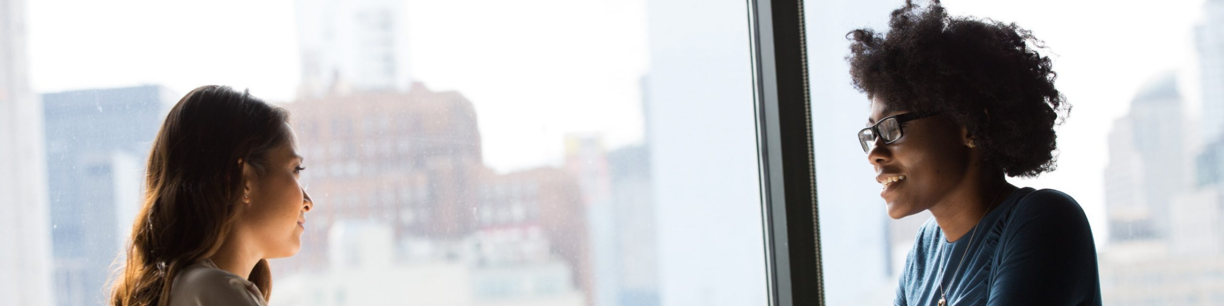 A meeting between two smiling, female members of staff.