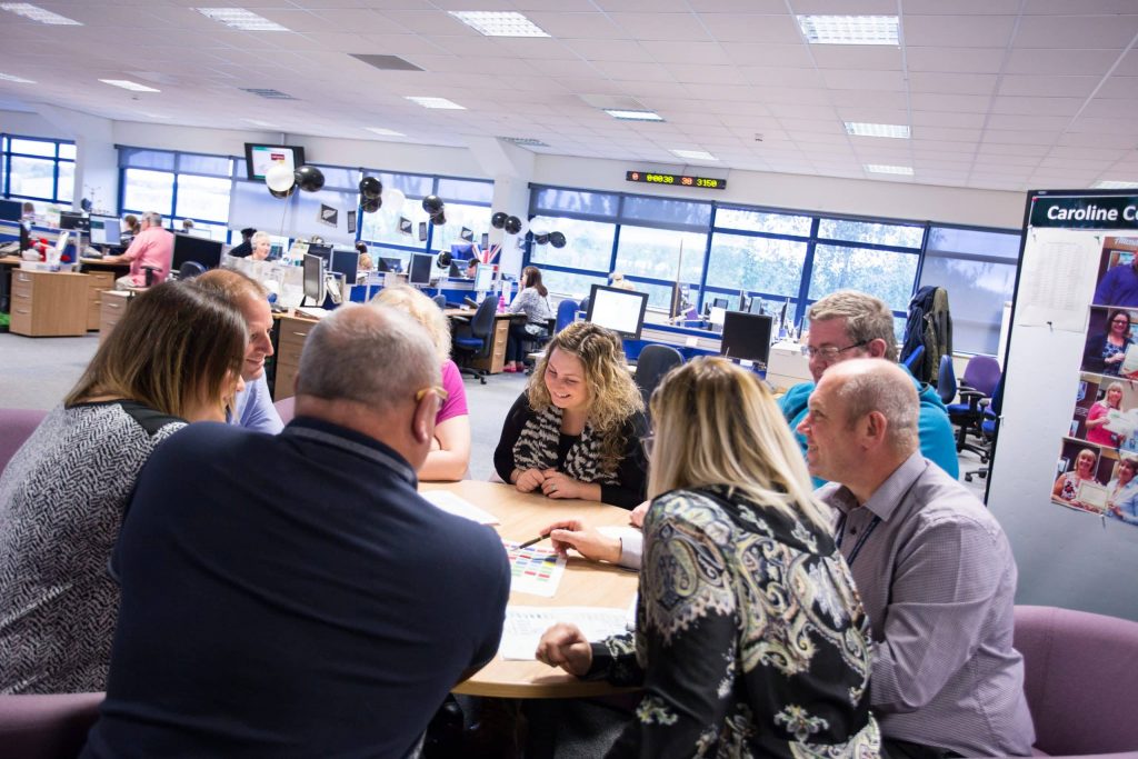 Operational Delivery team in discussion around a table.