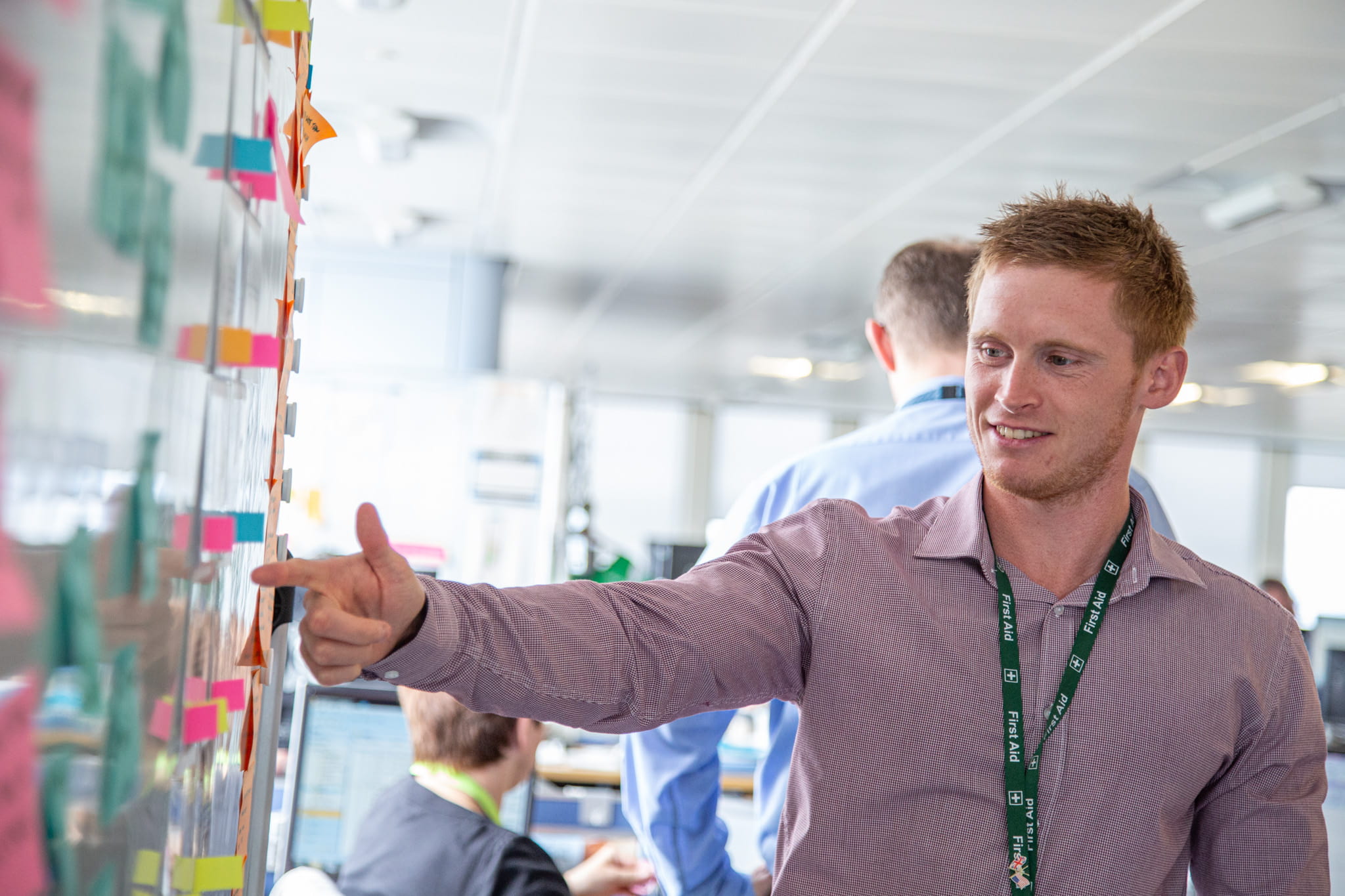 A DfT Statistician standing and pointing at a whiteboard presentation of colourful post-its to explain statistical insight.